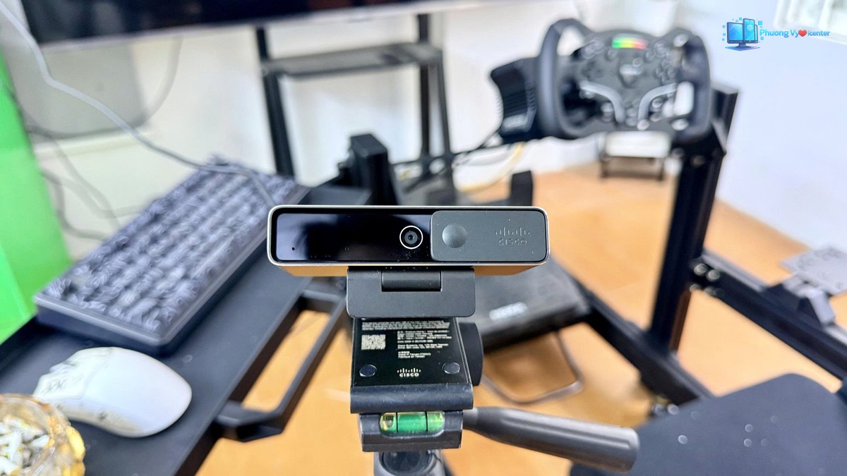 Webcam Cisco gắn trên chân máy, phía sau là màn hình và bàn phím