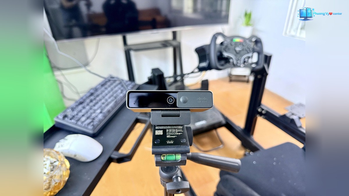 Webcam Cisco gắn trên chân máy, phía sau là màn hình và bàn phím