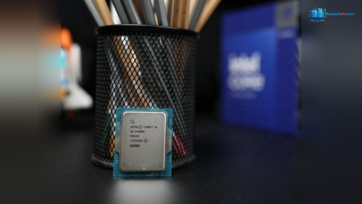 Intel Core i9-14900K dựng đứng trước ống đựng bút, hộp Intel Core mờ phía sau