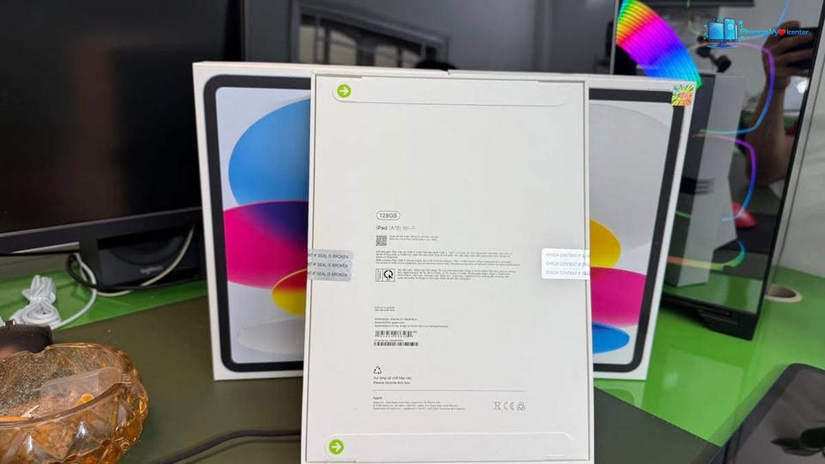 Các hộp Apple iPad A16 trên bàn, hộp giữa quay mặt sau có tem và thông tin sản phẩm