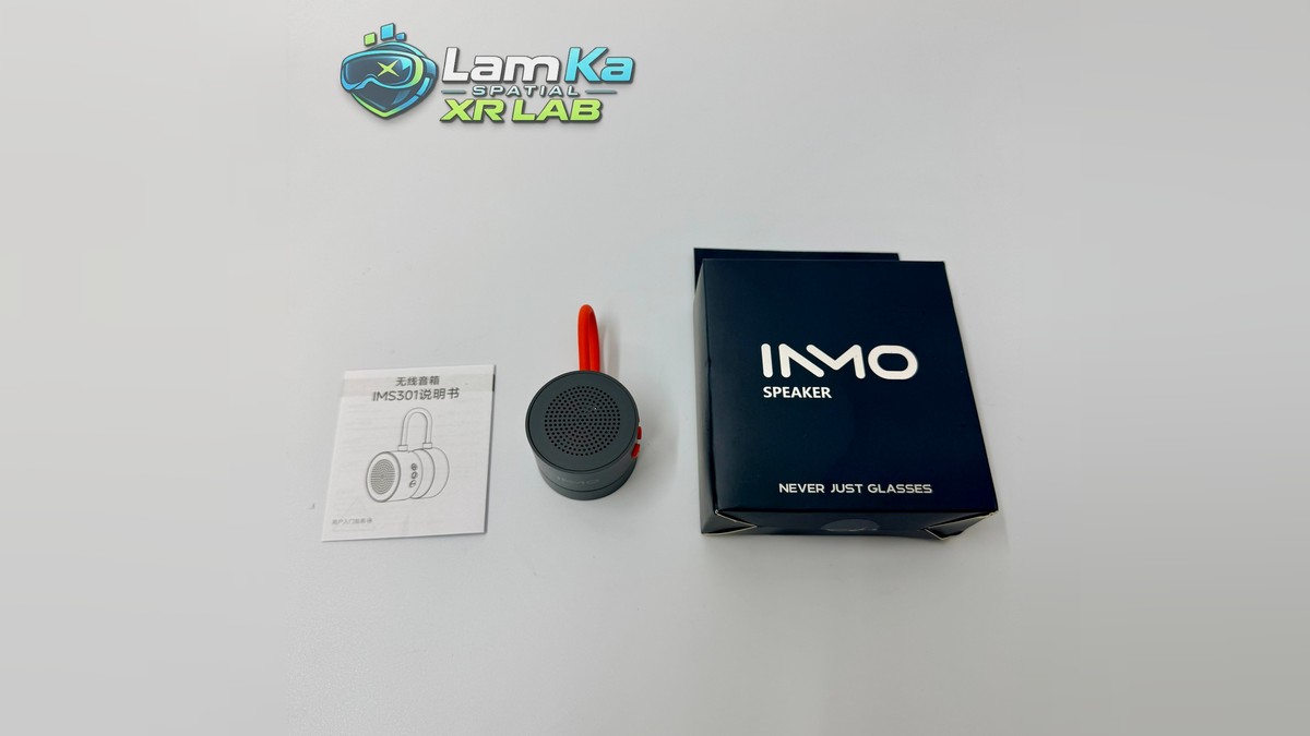 Loa INMO Speaker màu đen có quai đỏ, cạnh hộp sản phẩm và sách hướng dẫn