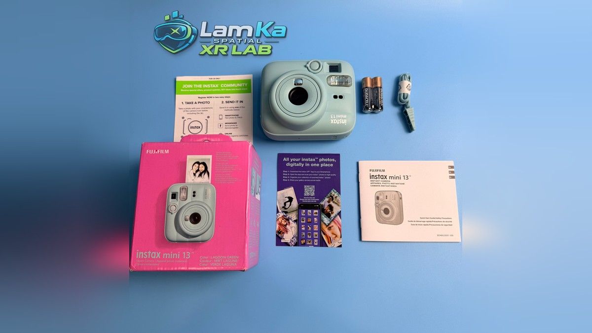 Fujifilm Instax Mini 13 cùng hộp hồng, hai viên pin, dây đeo và tài liệu