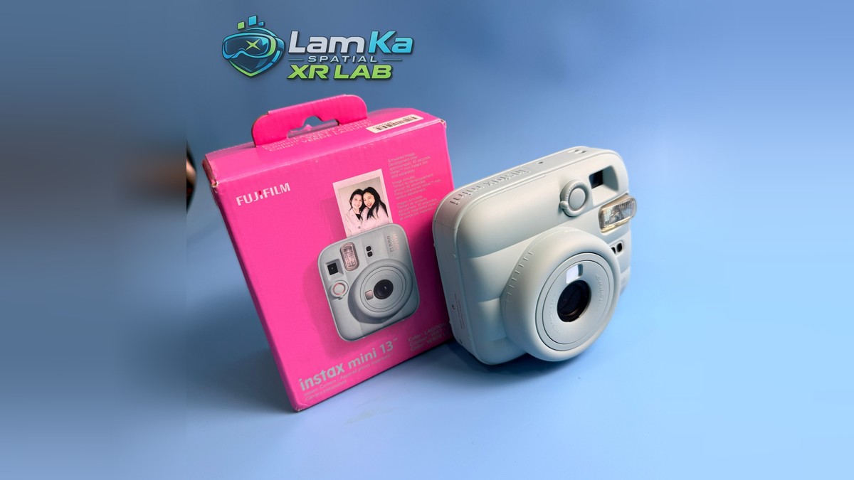 Fujifilm Instax Mini 13 chụp góc nghiêng, đặt cạnh hộp sản phẩm màu hồng