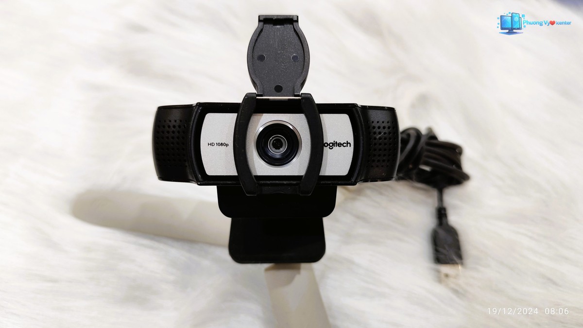 Webcam Logitech C930e nhìn từ phía trước, nắp che mở và chân kẹp trên nền trắng
